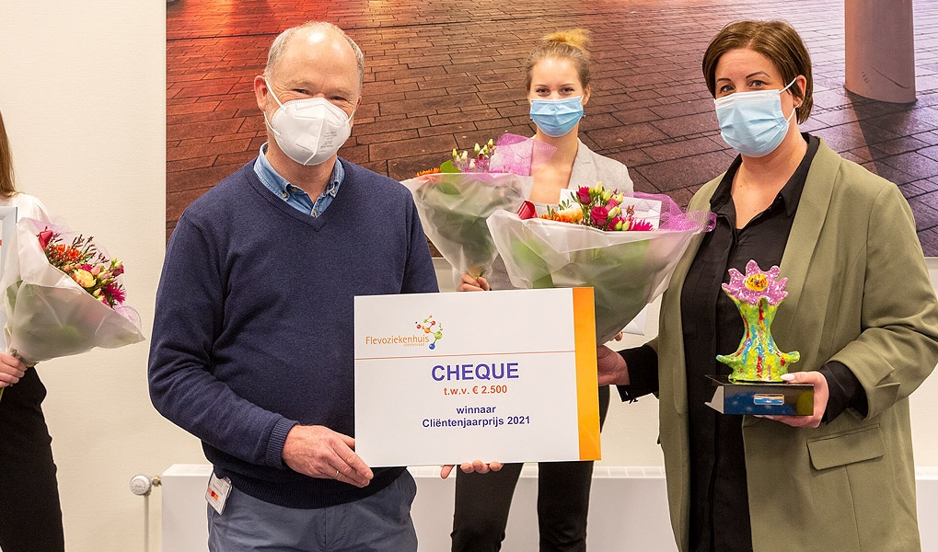 De voorzitter van de cliëntenraad Pim van den Toorn (midden) overhandigt de prijs aan Angela Halsema (rechts), teammanager van de afdeling Chirurgie van het Flevoziekenhuis. (Foto: aangeleverd)