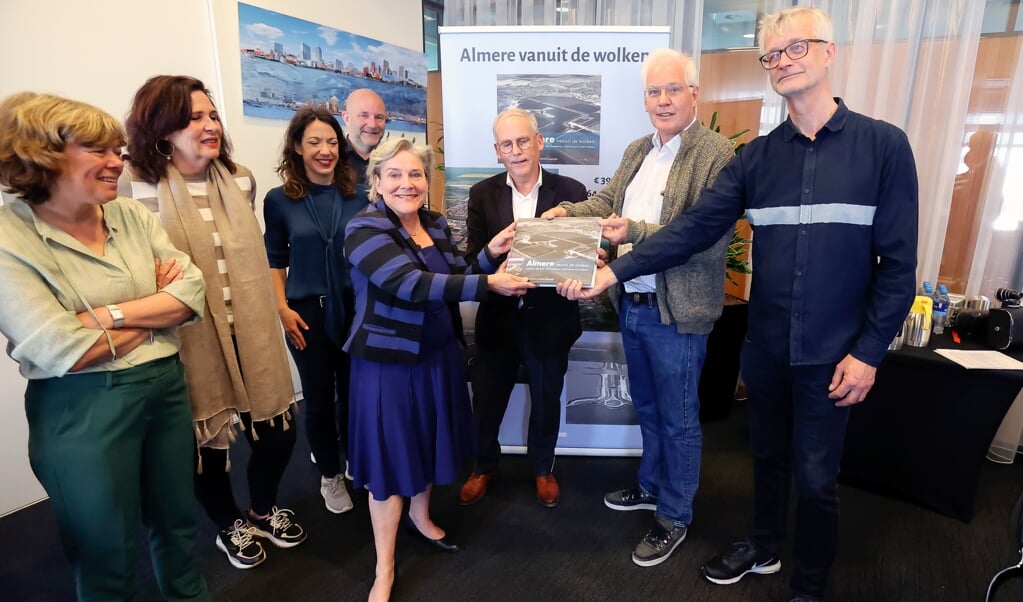 Het boek 'Almere vanuit de Wolken' werd dinsdag door Michel Langendijk (rechts), fotograaf Roel Dijkstra en uitgever Peter Egge overhandigd aan het Almeerse college. Waarnemend burgemeester Ank Bijleveld nam het eerste exemplaar in ontvangst. (Foto: Fred Rotgans)