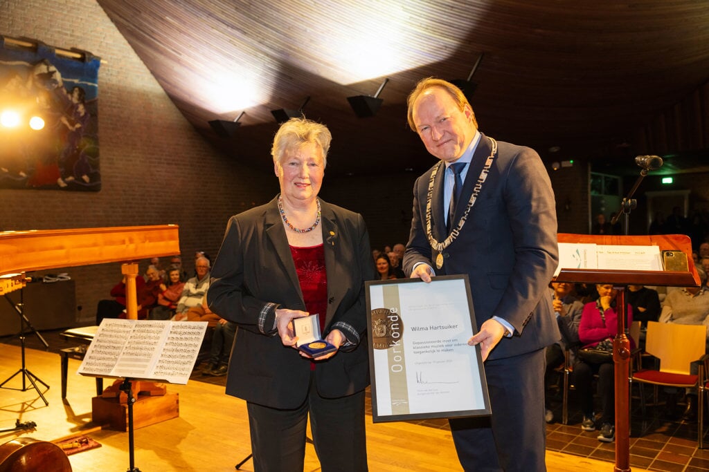 Burgemeester Hein van der Loo verraste Wilma Hartsuiker van Goede Rede Concerten met de gemeentelijke erepenning. (Foto: Gemeente Almere/Maarten Feenstra)