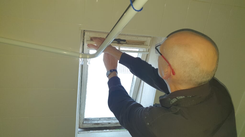 Raadslid Rijk Ravestein inspecteert het raam dat is uitgezet door het vocht. (Foto: Almere DEZE WEEK)