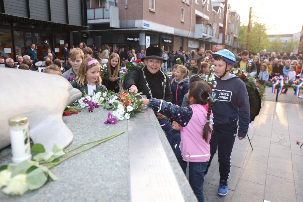 Waarnemend burgemeester Ank Bijleveld legt samen met Almeerse kinderen bloemen bij het monument De Dolfijn in Haven. (Foto: Fred Rotgans)