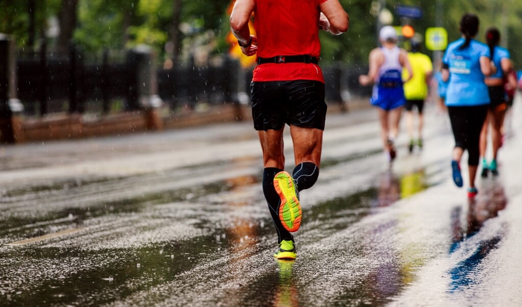 group of runners men and women running under rain drops city marathon