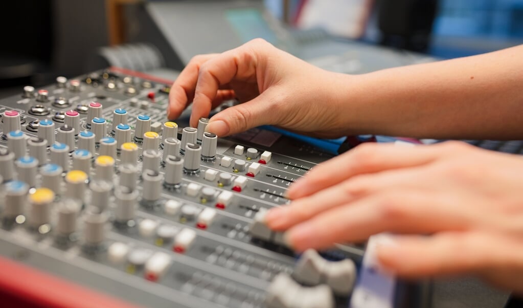 Female radio host using adusting volume at music mixer in radio studio. Sound music in professional studio.