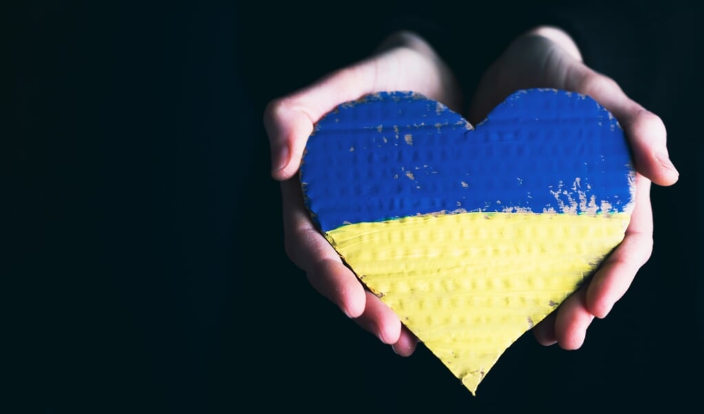 Heart shaped flag of Ukraine in female hands with copy space. The concept of solidarity with the citizens of Ukraine.
