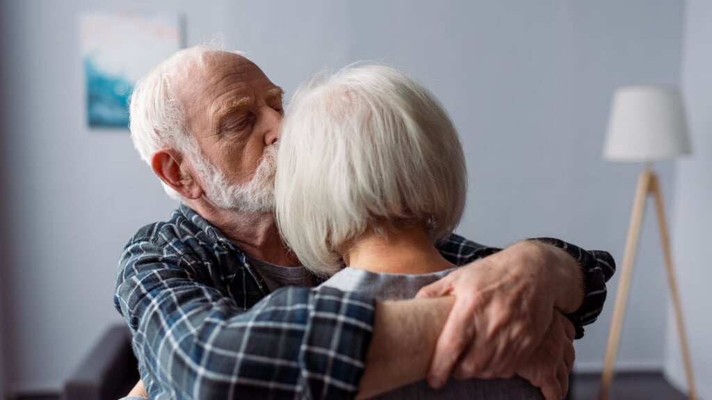 senior man hugging and kissing wife, suffering from alzheimer disease