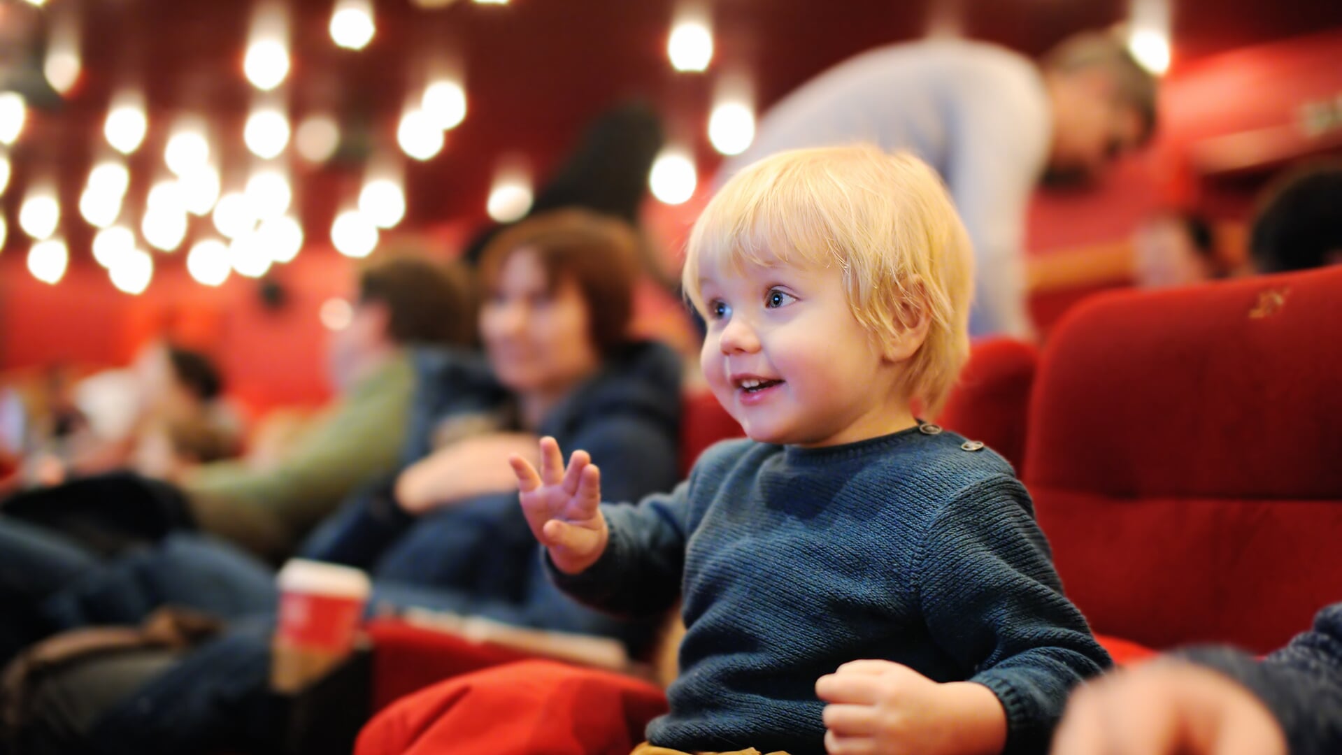 Cute toddler boy watching cartoon movie in the cinema. Leisure/entertainment for family with kids.