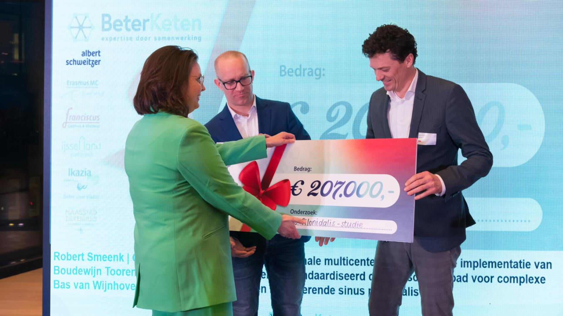Marlise Schouten, directeur van Stichting BeterKeten, reikt de symbolische cheque van 207.000 euro uit aan de chirurgen Smeenk en Toorenvliet (rechts).