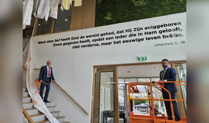 Wethouder Platschorre (links met schaar) en oud-wethouder Flach onthulden Bijbeltekst in speellokaal Stadhouder Willem III school.