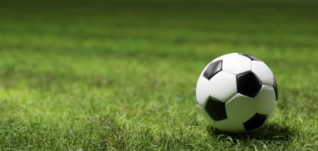 Football soccer ball on grass field in spotlight