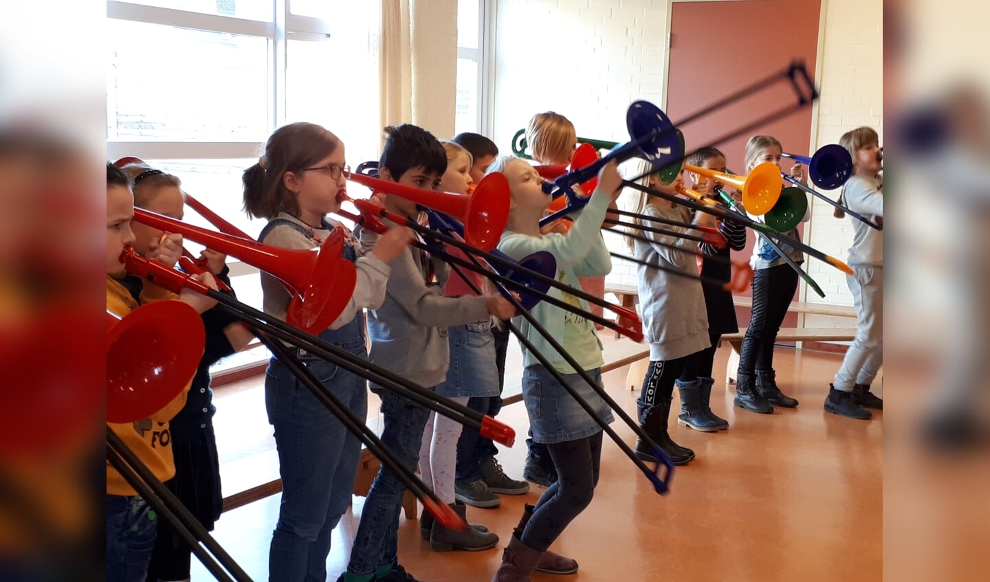 Kinderen spelen op kunststof trombone's tijdens de presentatieles