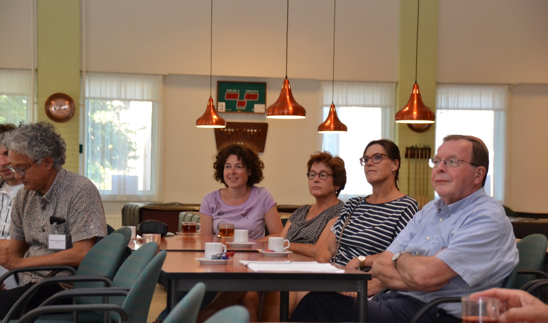 Bezoekers van de inloopavond over windmolens luisteren naar de uitleg van wethouder Andrew Harijgens. 