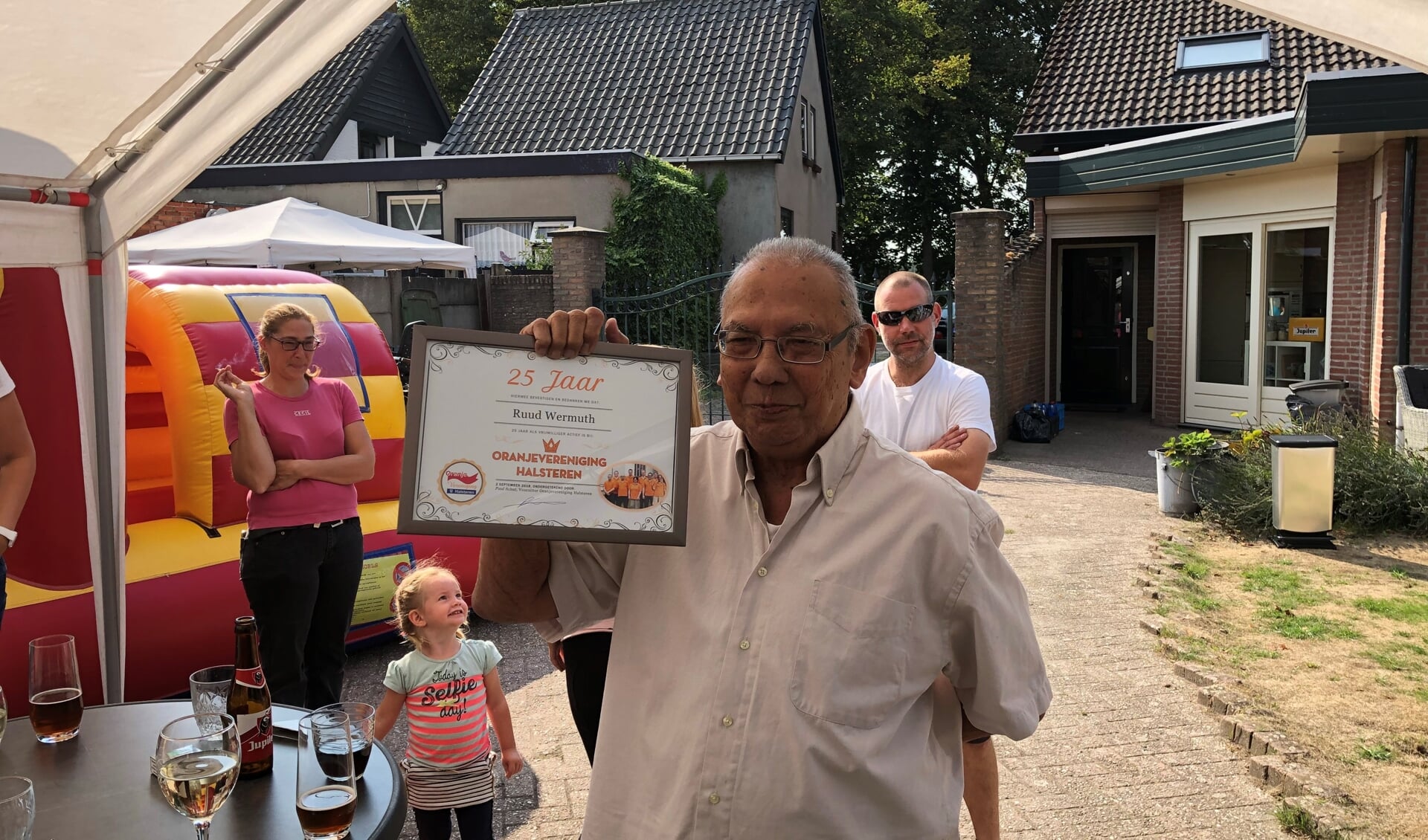 Ruud Wermuth toont de oorkonde die hij van Oranjevereniging Halsteren ontving vanwege 25 jaar vrijwillige inzet. Ook vrijwilliger Norman Kuijpers werd in het zonnetje gezet.
