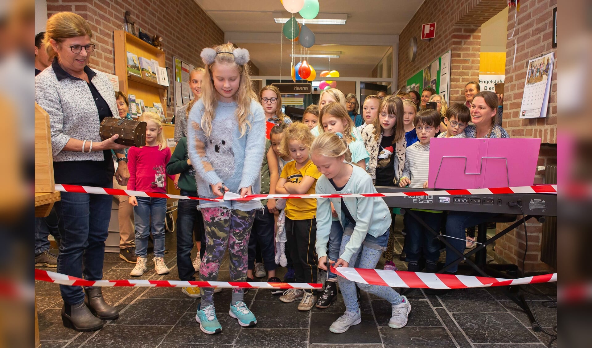 Twee linten werden er  doorgeknipt en daarna namen de mini Krekels en het Krekelkoor vol enthousiasme het aanwezige publiek mee op hun muzikale reis waarmee de Kinderboekenweek in de bibliotheek van Huijbergen officieel was geopend.