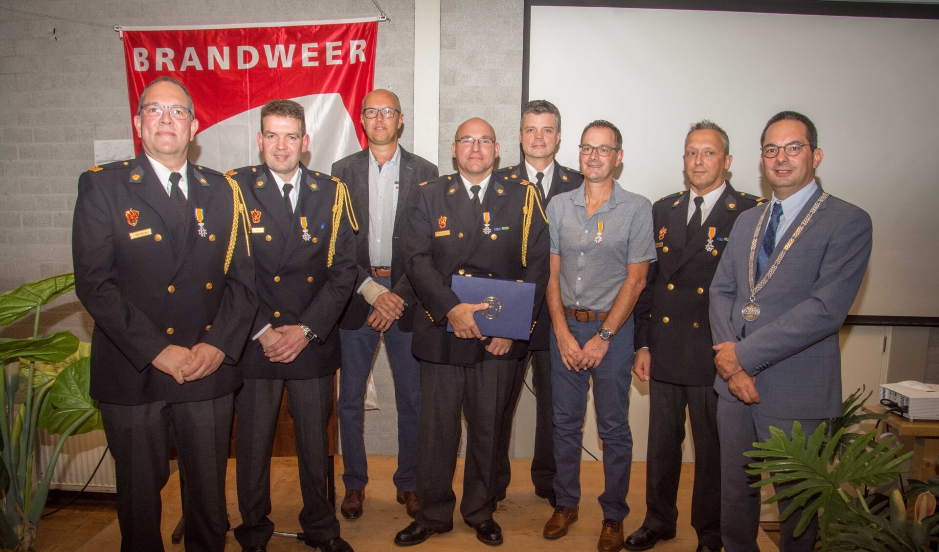 Burgemeester Adriaansen met de gedecoreerde brandweervrijwilligers.
