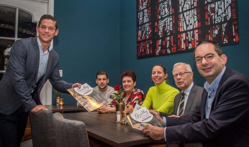 Onder toeziend oog van enkele horecacollega's "serveert" Ruud de Weert de brochure.