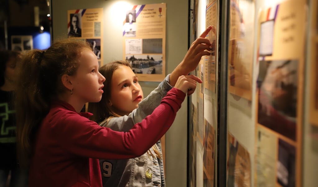 Schoolkinderen bekijken aandachtig de tentoonstelling over de Tweede Wereldoorlog die is opgezet bij heemkundekring Halchterth.