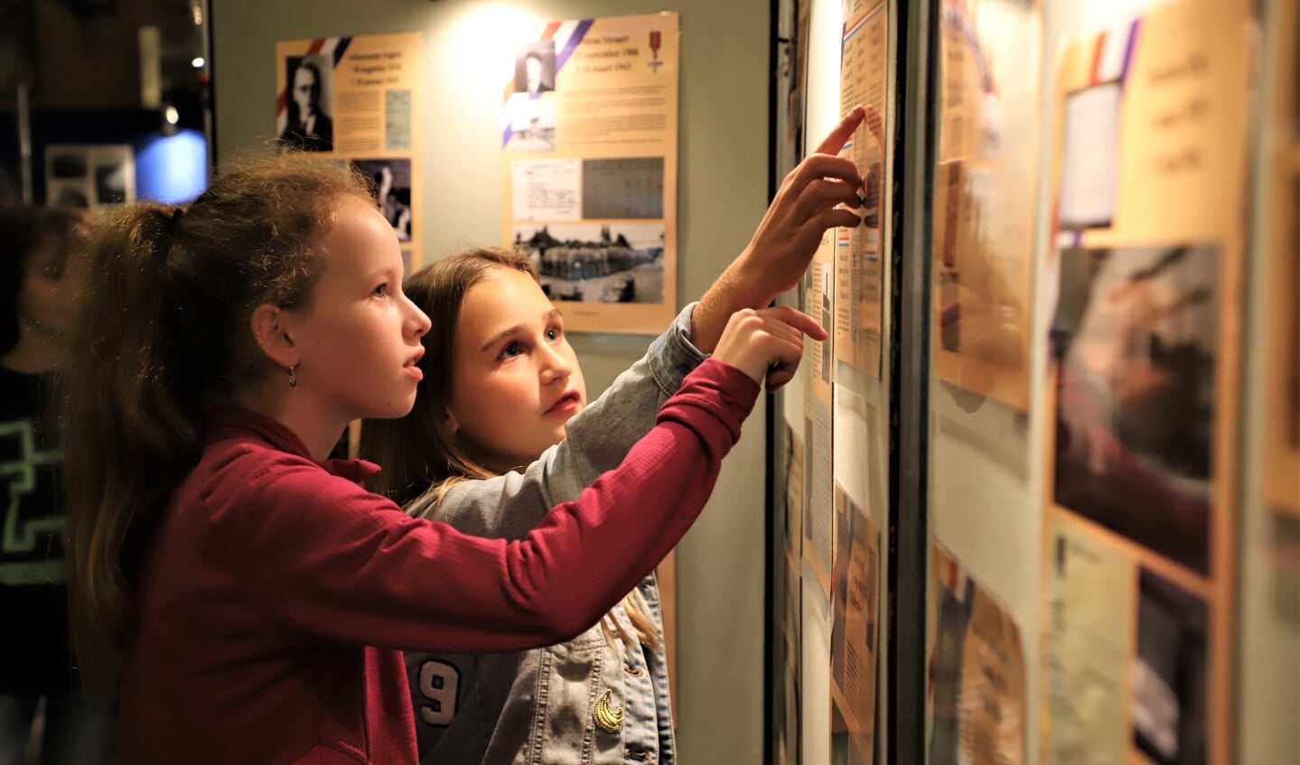 Schoolkinderen bekijken aandachtig de tentoonstelling over de Tweede Wereldoorlog die is opgezet bij heemkundekring Halchterth in Hof van Ram. 