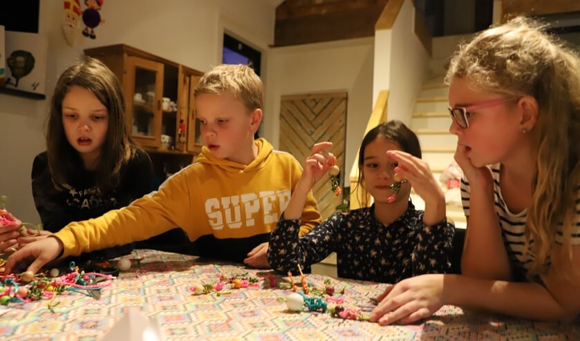 Kinderen van buitenschoolse opvang Zo op 't Groene Hart knutselen gelukspoppetjes bij dagbesteding 'op 't Dorp' voor de kerstmarkt.