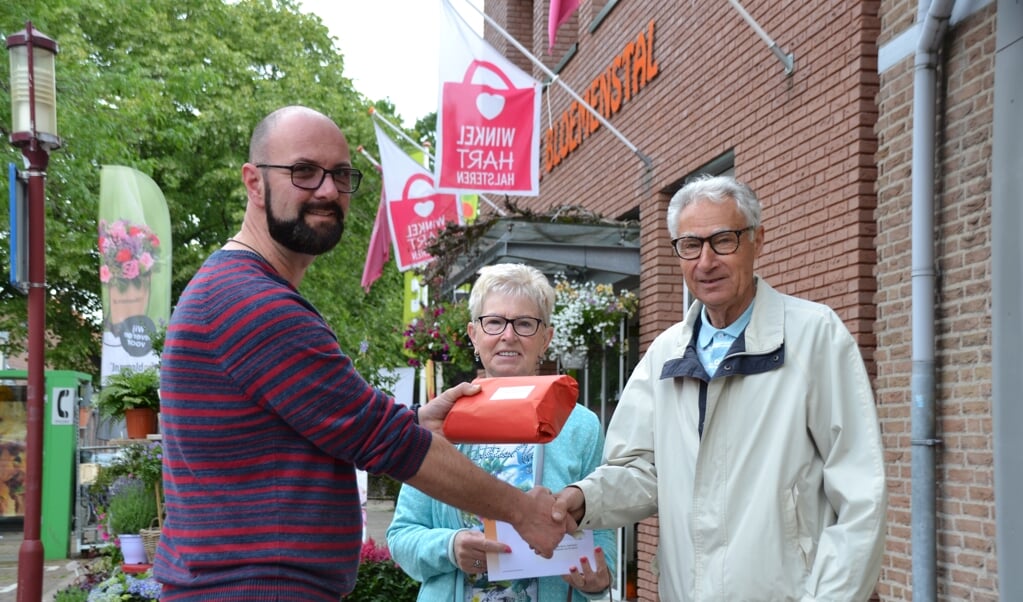 Secretaris Marc Hellemons van WinkelHart Halsteren overhandigt de prijs aan fanatieke puzzelaars Marlene Schoutens en Bert Hagenaars. Zij zijn twee van de 29 winnaars van mooie prijzen, die beschikbaar zijn gesteld door  leden van WinkelHart Halsteren.