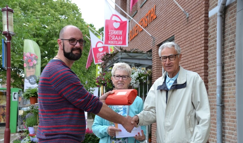 Secretaris Marc Hellemons van WinkelHart Halsteren overhandigt de prijs aan fanatieke puzzelaars Marlene Schoutens en Bert Hagenaars. Zij zijn twee van de 29 winnaars van mooie prijzen, die beschikbaar zijn gesteld door leden van WinkelHart Halsteren.