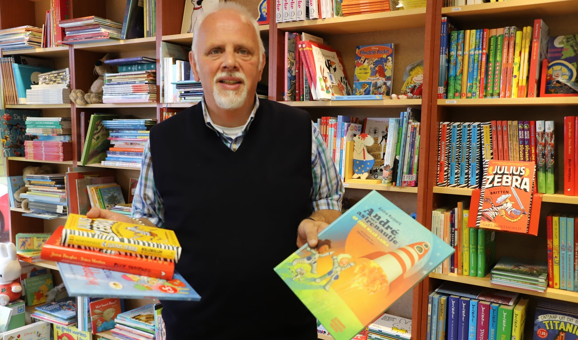 Joost Vermeulen voor de schappen vol uiteenlopende boeken voor kinderen van alle leeftijden in zijn voormalige boekhandel.