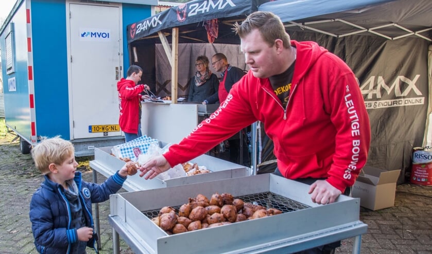 Gert-Jan Veraart geeft een jonge bezoeker een oliebol.