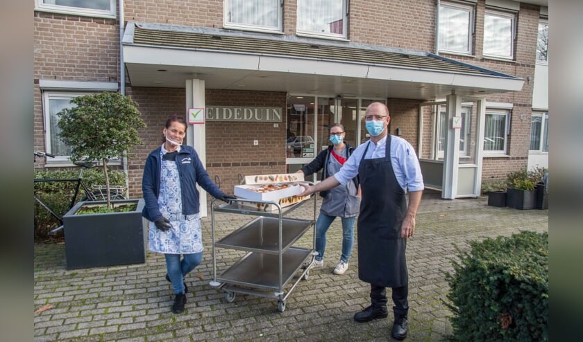 <p>Lieske Keijzer overhandigt de oliebollen aan het personeel van zorgcentrum Heideduin.</p>