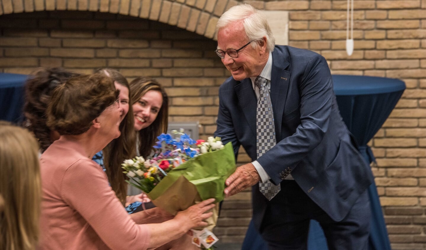 Scheidend wethouder Henk Kielman geeft de bloemen die hij krijgt aan zijn echtgenote Liesbeth.