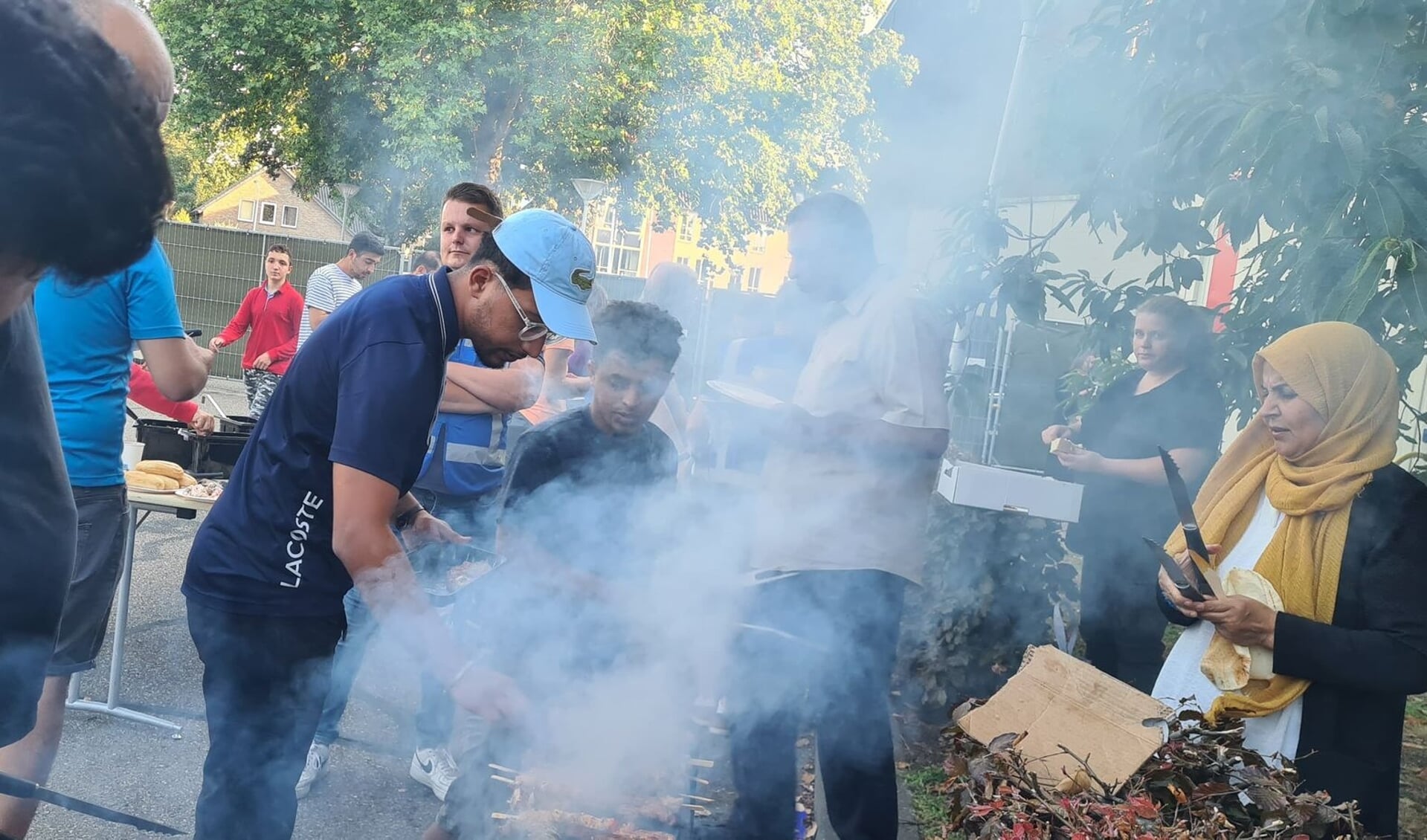 Vluchtelingen bereidden het eten op de barbecue voor vrijwilligers in Kloosterhof. 
