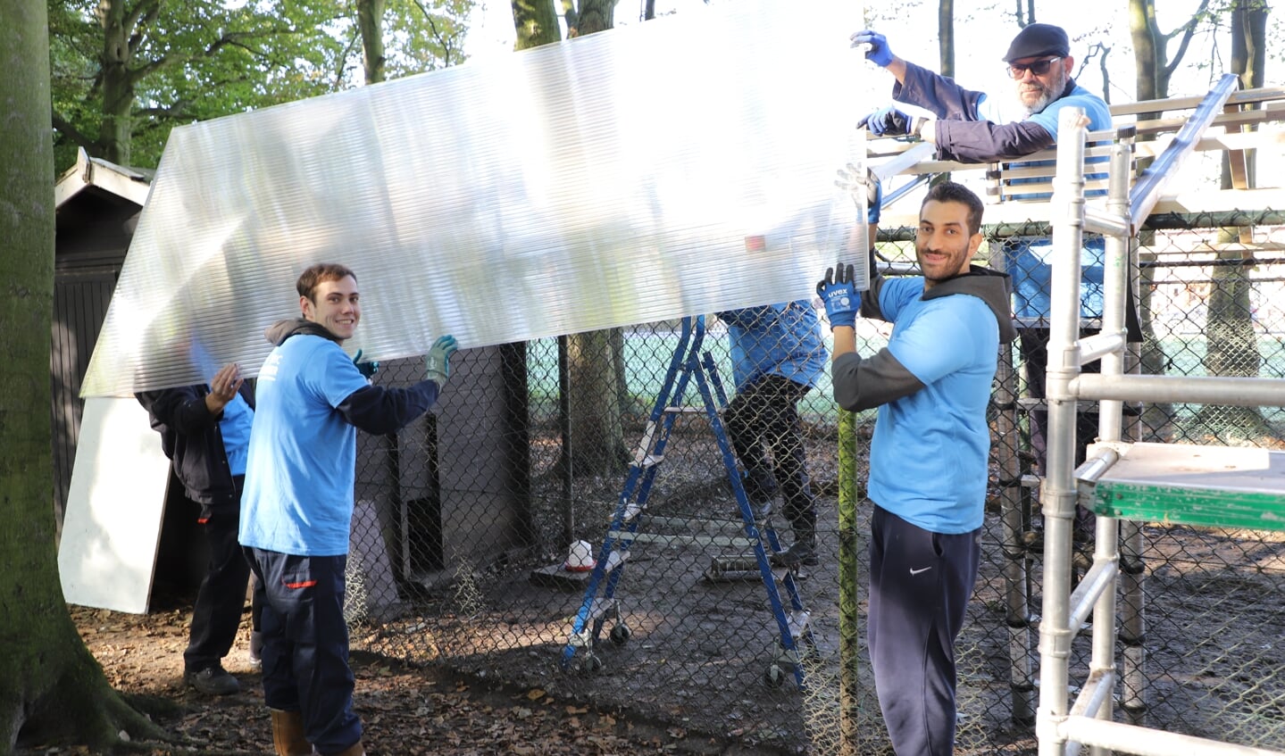 Volunteers van SABIC leggen permanente bedekking op de vogelkooi in het hertenkamp.