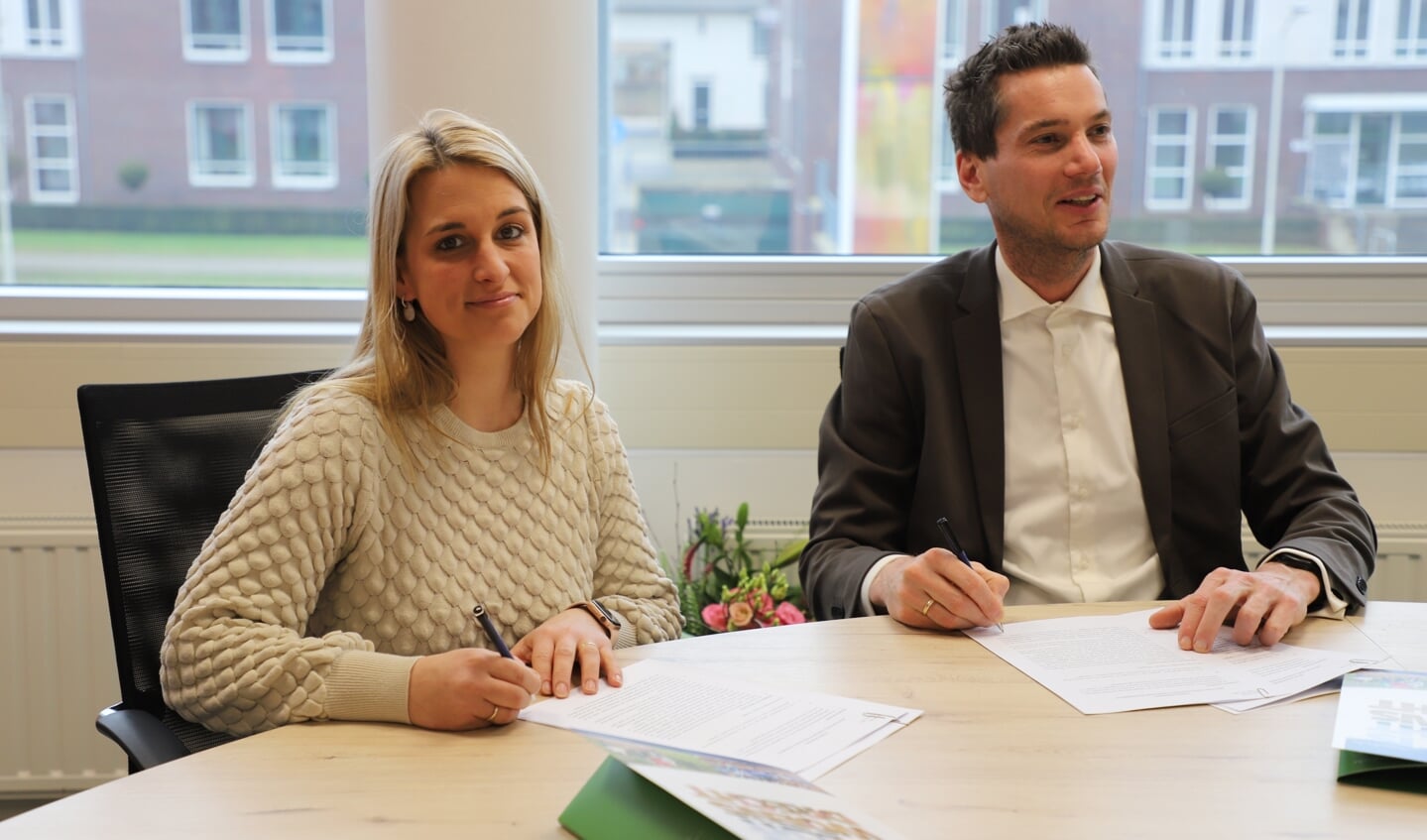 Sabrina Pijnen en wethouder Jeffrey van Agtmaal tekenen de overeenkomst voor het beheer van MFC De Drieschaar.