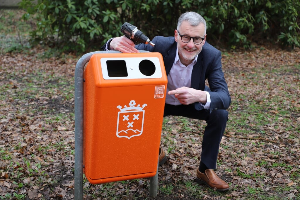 Wethouder Hans-Peter Verroen wijst op de QR-code op de nieuwe afvalbak.