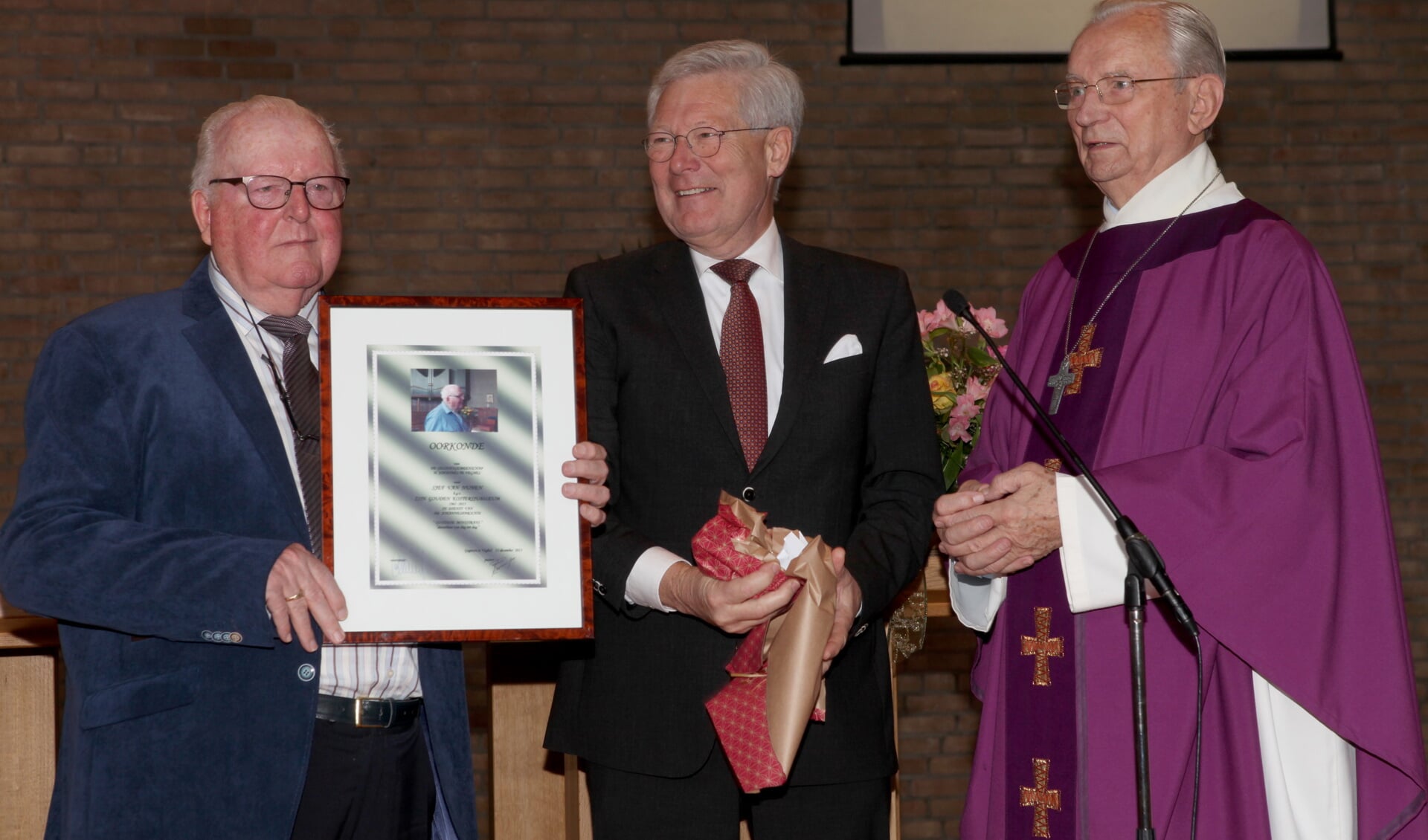 Een oorkonde voor Sjef van Nunenen (L) naast hem Sjang van Hout en Pastor Konings. (Foto: Peter Kuijpers)