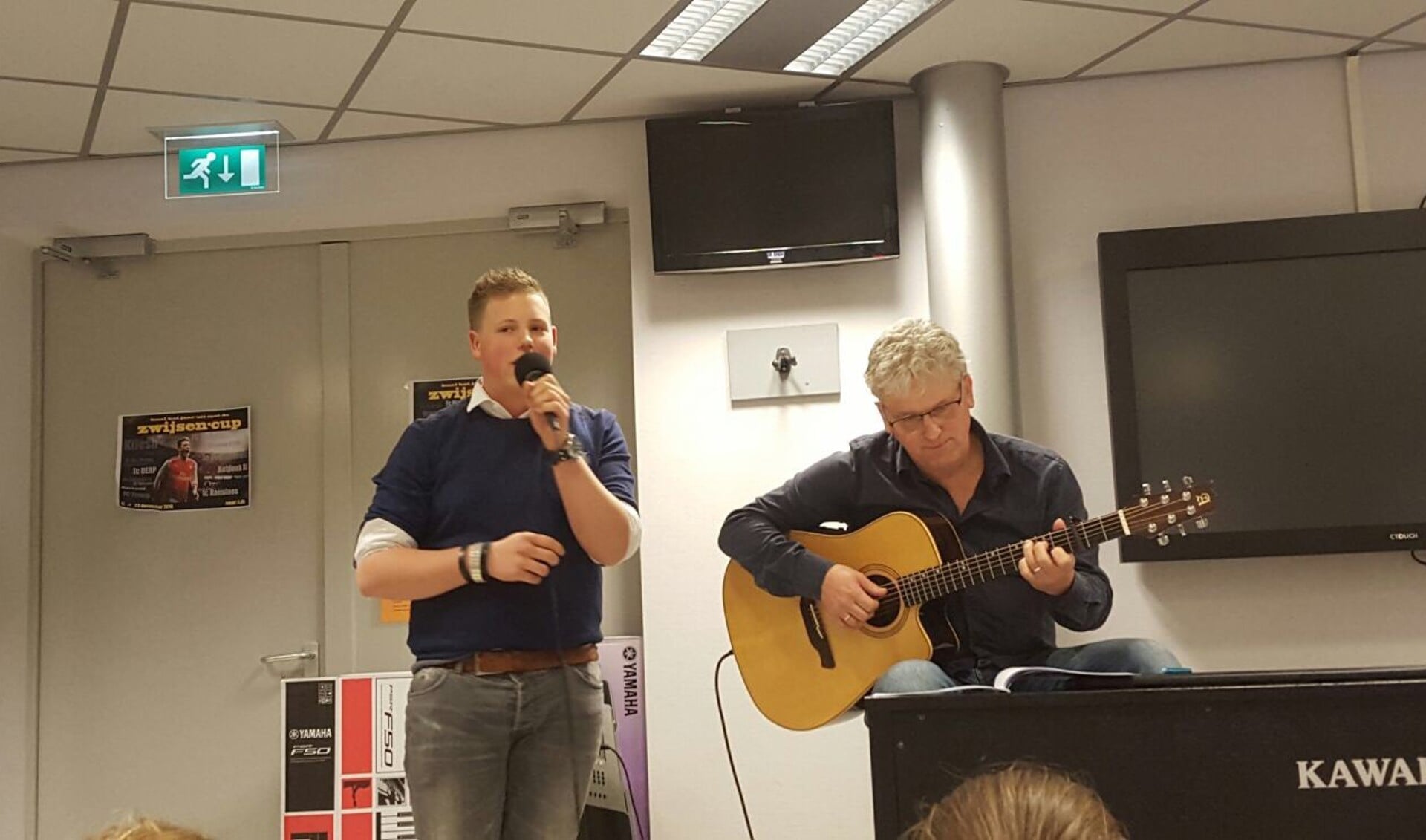 Stan van Hoof zingt tijdens zijn albumpresentatie op het Zwijsen afgelopen dinsdag. Muziekdocent meneer Van Hoof begeleidt hem op gitaar.