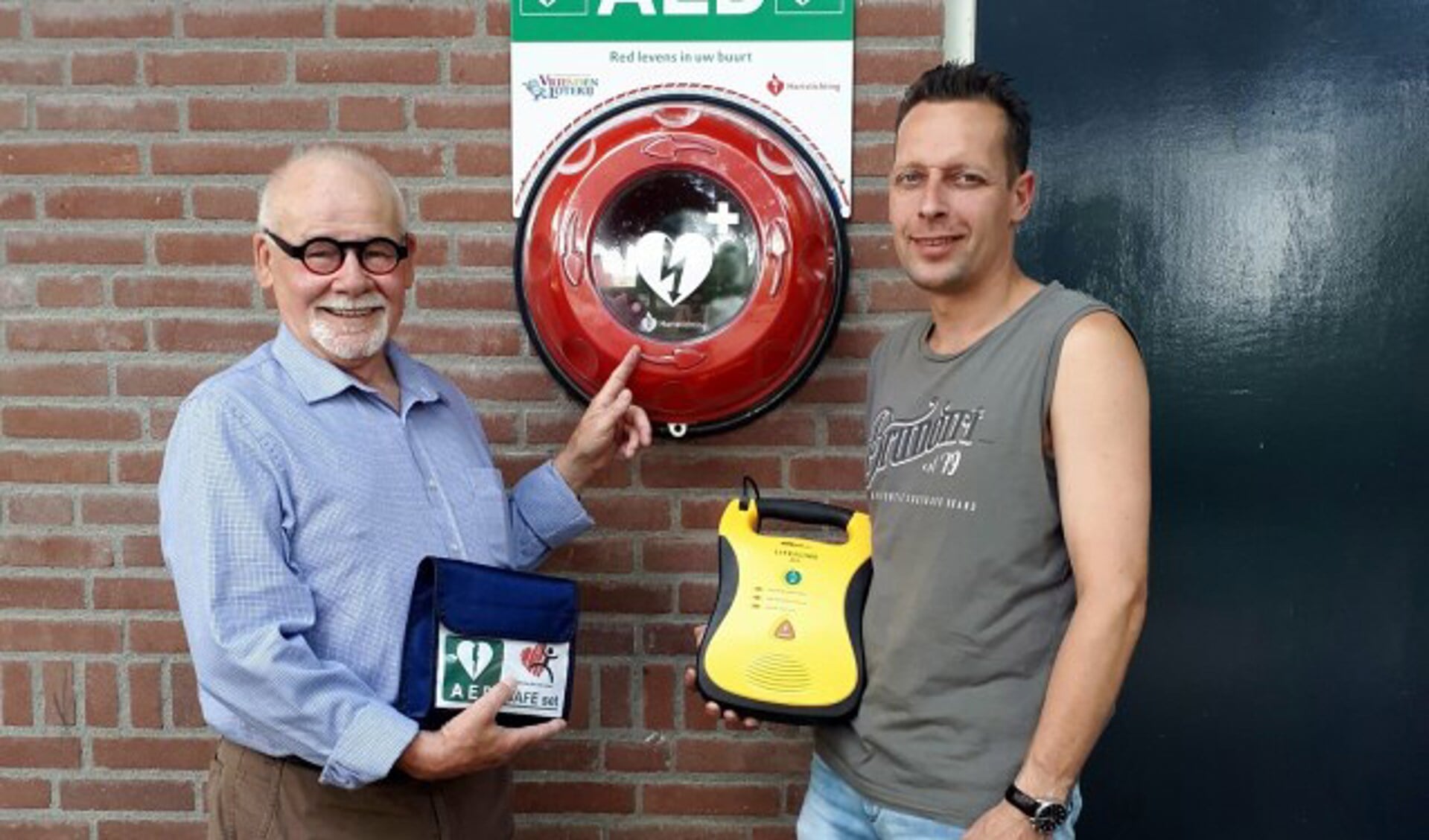 AED-voorvechter Toon Hermsen uit Mill (links) in juli van dit jaar bij een nieuwe AED-buitenkast bij het voetbalveld in Sint Hubert.