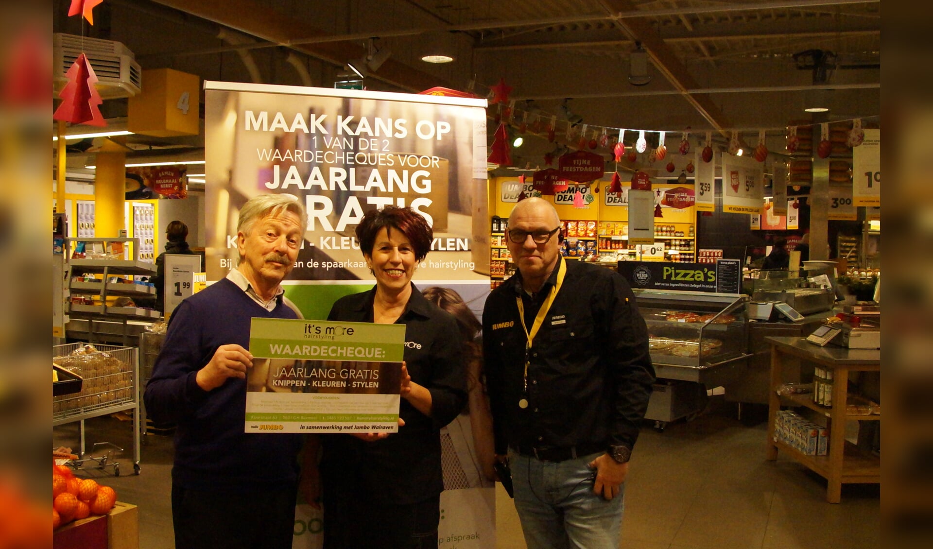 De heer Schuddeboom ontvangt de prijs uit handen van kapster Annemarie en Jumbo-medewerker Martijn Cleijne. 