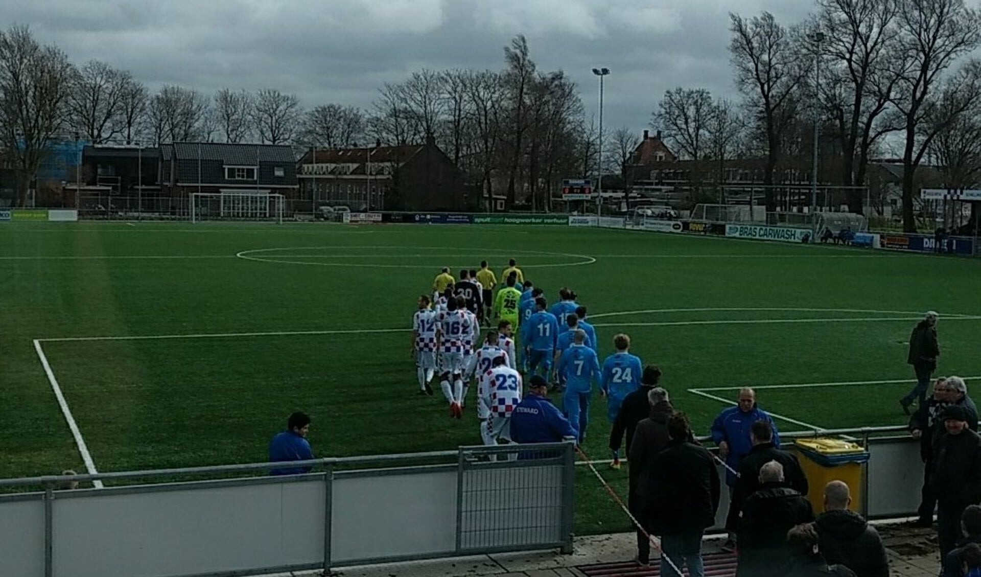 Spelers komen het veld op in een winderig Amsterdam (Foto: De Dijk)