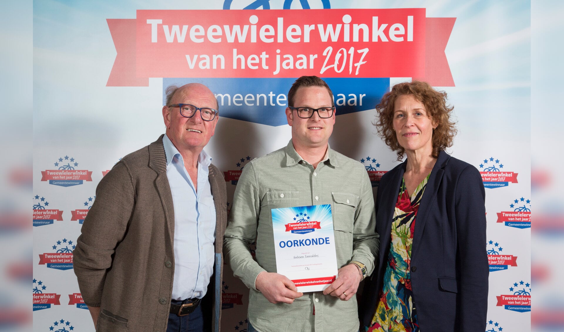 Nico (l) en Niels Verboven ontvangen de oorkonde uit handen van Annemarie Visser van het vakblad Tweewieler.