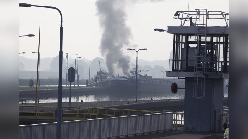 Rookwolken komen uit het schip dat in een sluis in Sambeek ligt. Foto: SK-Media