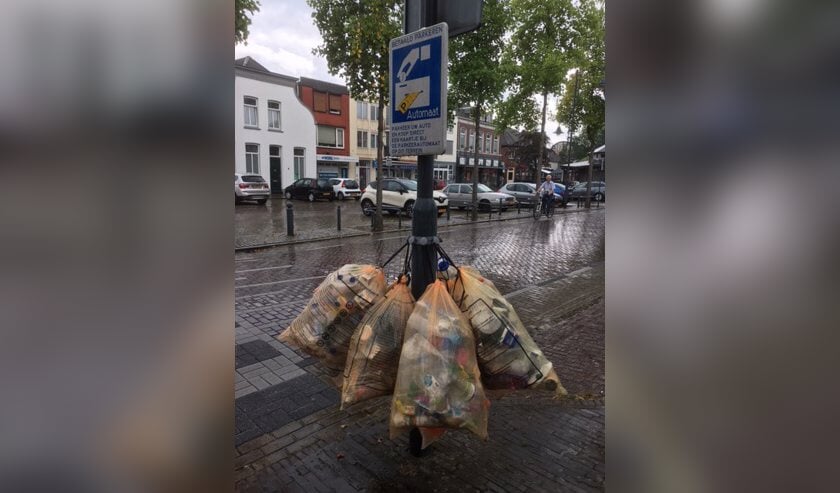 De volle afvalzakken aan een lantaarnpaal