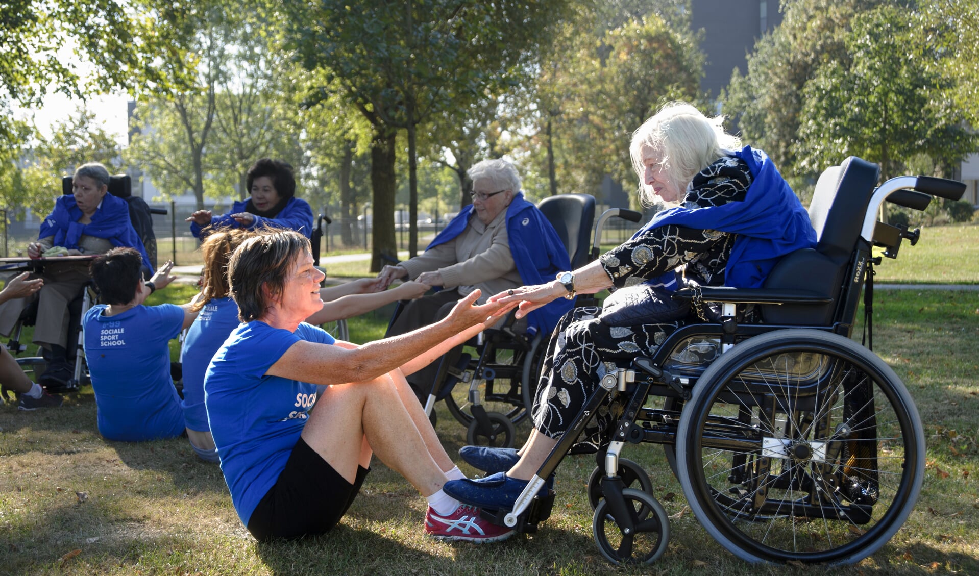 Sporters gaan met ouderen in een rolstoel samen op bootcamp. 