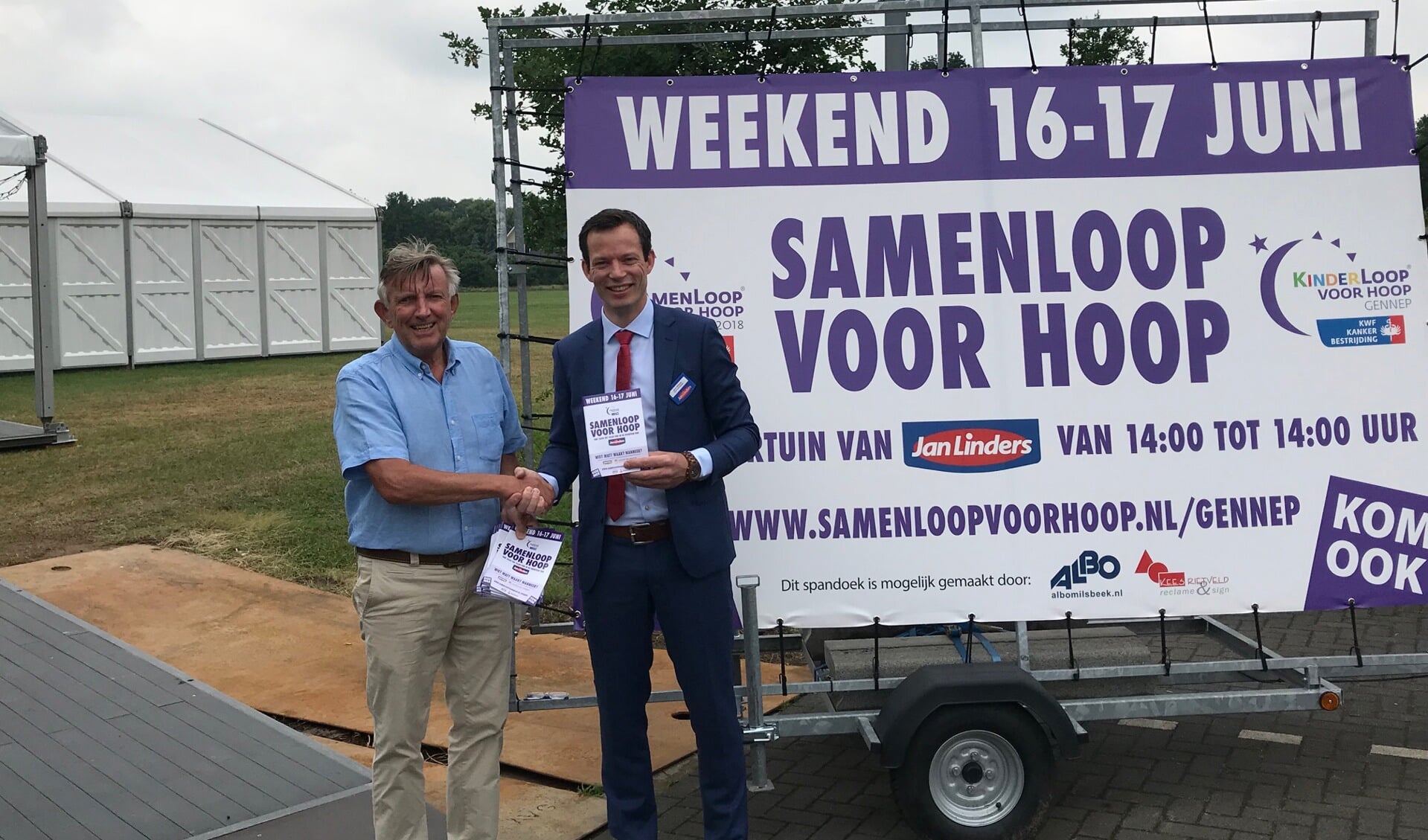 Vestigingsmanager Jacco Dijkema (rechts) neemt de eerste programmaboekjes in ontvangst van SamenLoop Gennep voorzitter Teus van Leeuwen voor het terrein waar het komend weekend allemaal gaat gebeuren.