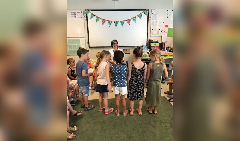 Juf Ella omringd door 'haar' kinderen