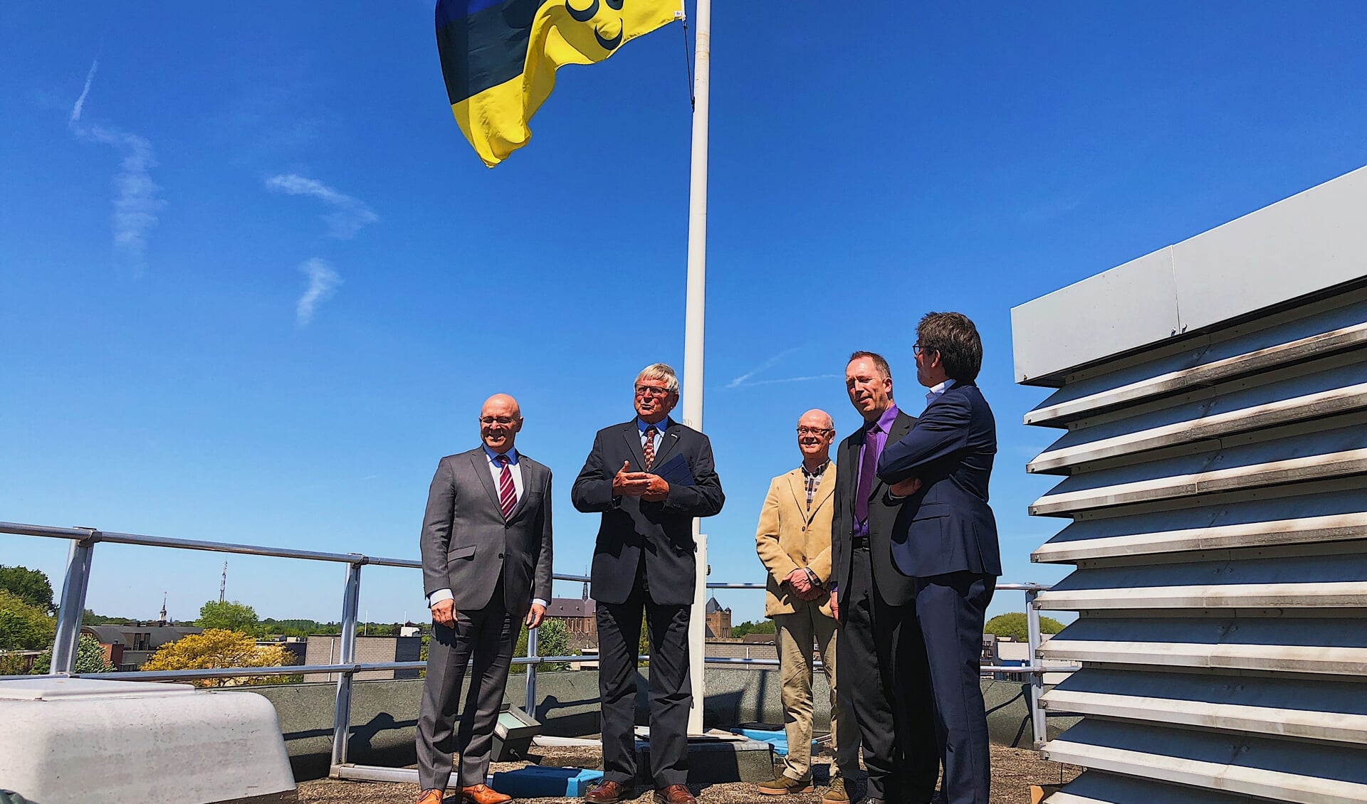 De nieuwe vlag wappert boven de hoofdrolspelers van afgelopen woensdag. Ook burgemeester Kees van Rooij (uiterst links) was aanwezig. 