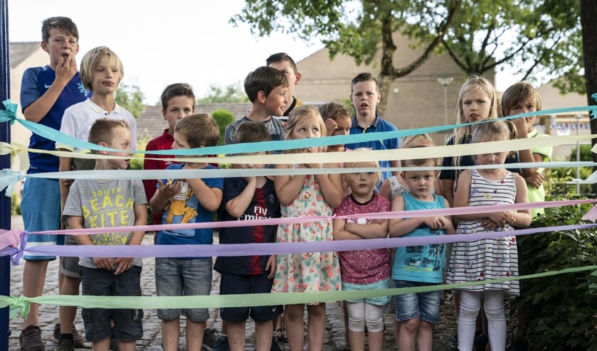 De kinderen wachten tot ze de linten mogen doorknippen en lekker kunnen spelen in de vernieuwde speeltuin.
