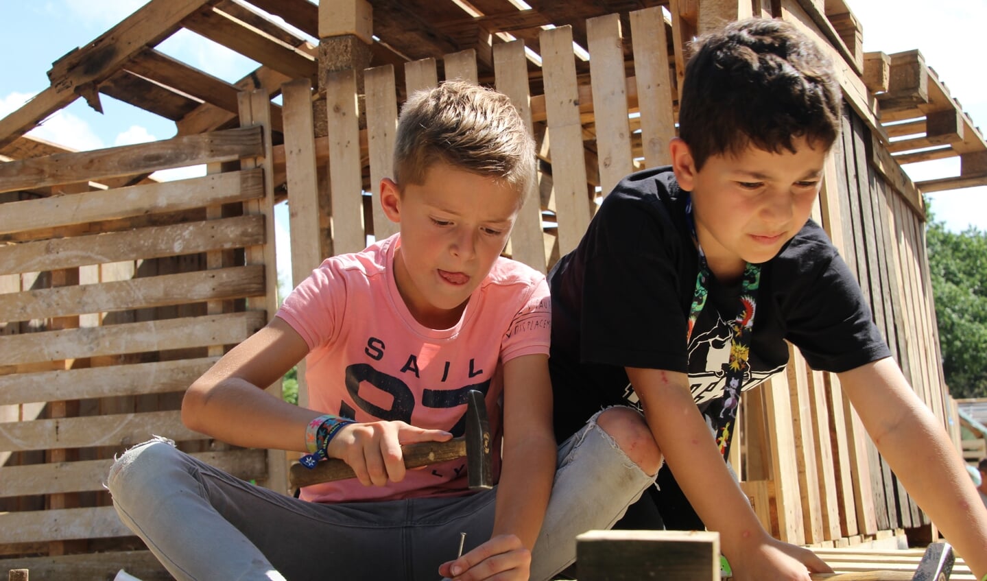 Lars en Christos zijn allebei 8 jaar oud. Ze zijn samen hard aan het werk om het dak te verstevigen. 
