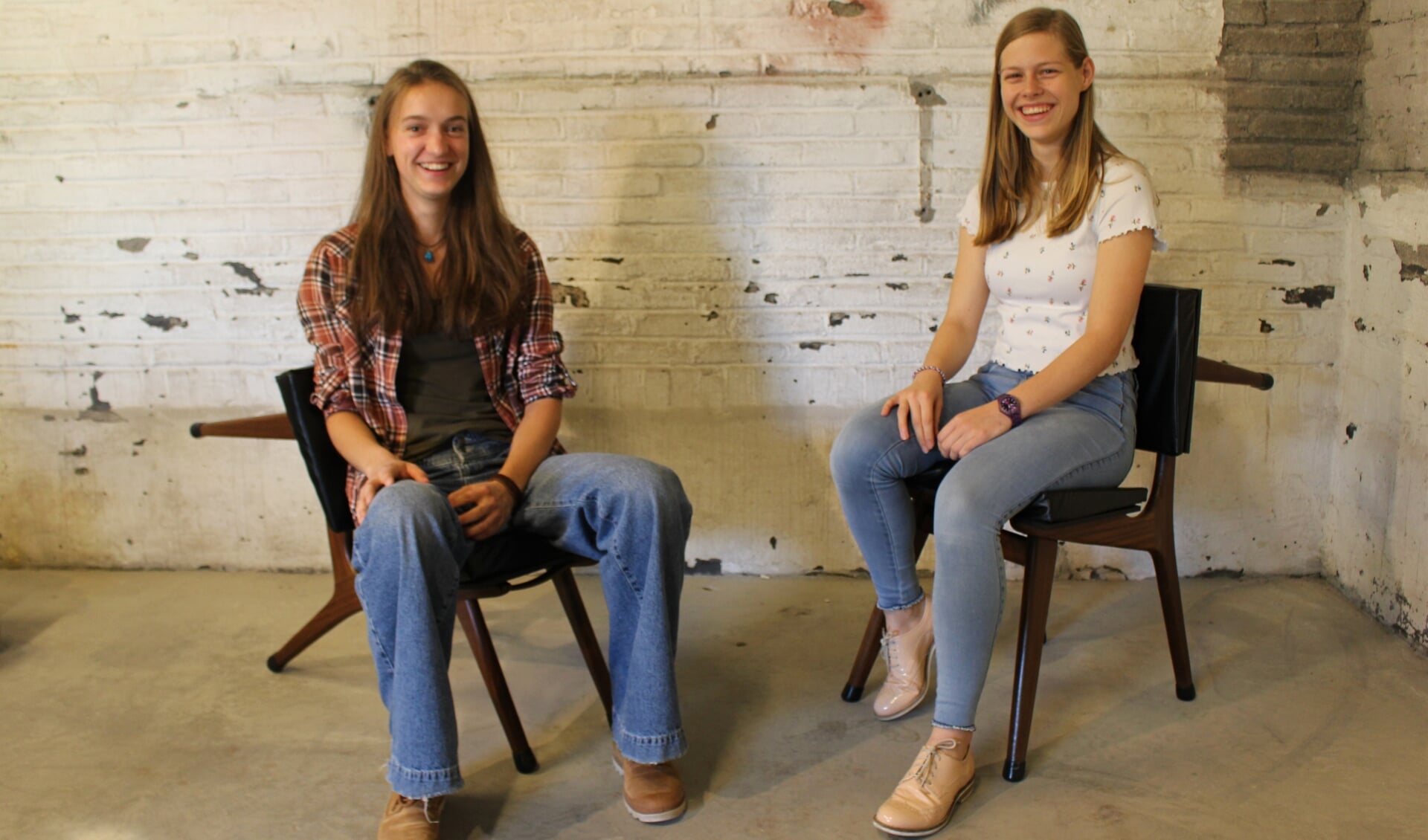 Aila (L) en Yara in hun expositieruimte. Ze zitten op de ontworpen stoelen van Aila.