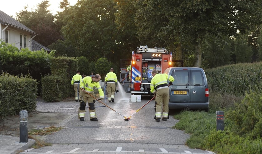 De brandweer reinigt olie op de Kampsestraat in Haps.