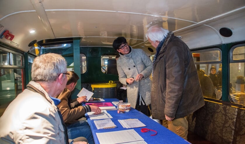 <p>Nol van Hest (R) staat een bezoeker te woord in de mobiele stembus. Iets wat tijdens de komende verkiezingen niet op deze manier mag.</p>