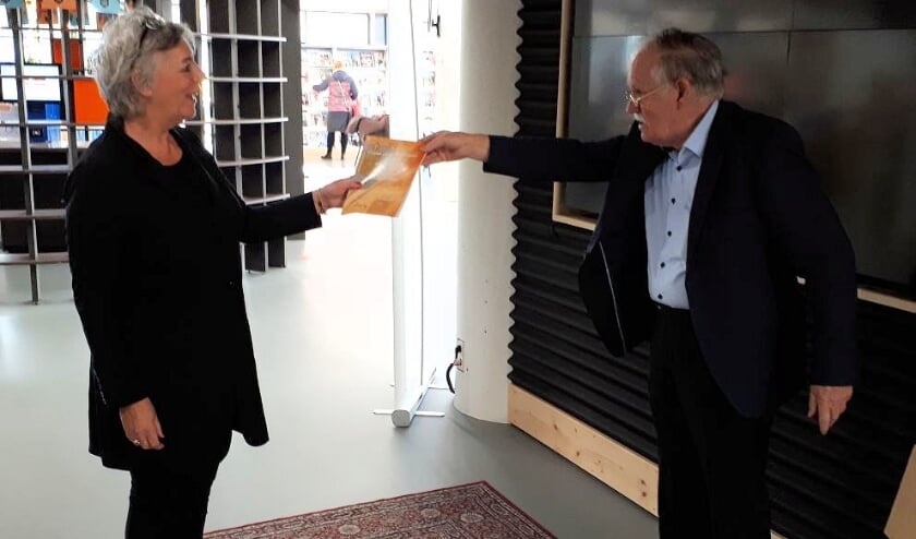 <p>Schrijver Adriaan Sanders reikt het eerste boekje uit aan Karin van de Ven.</p>